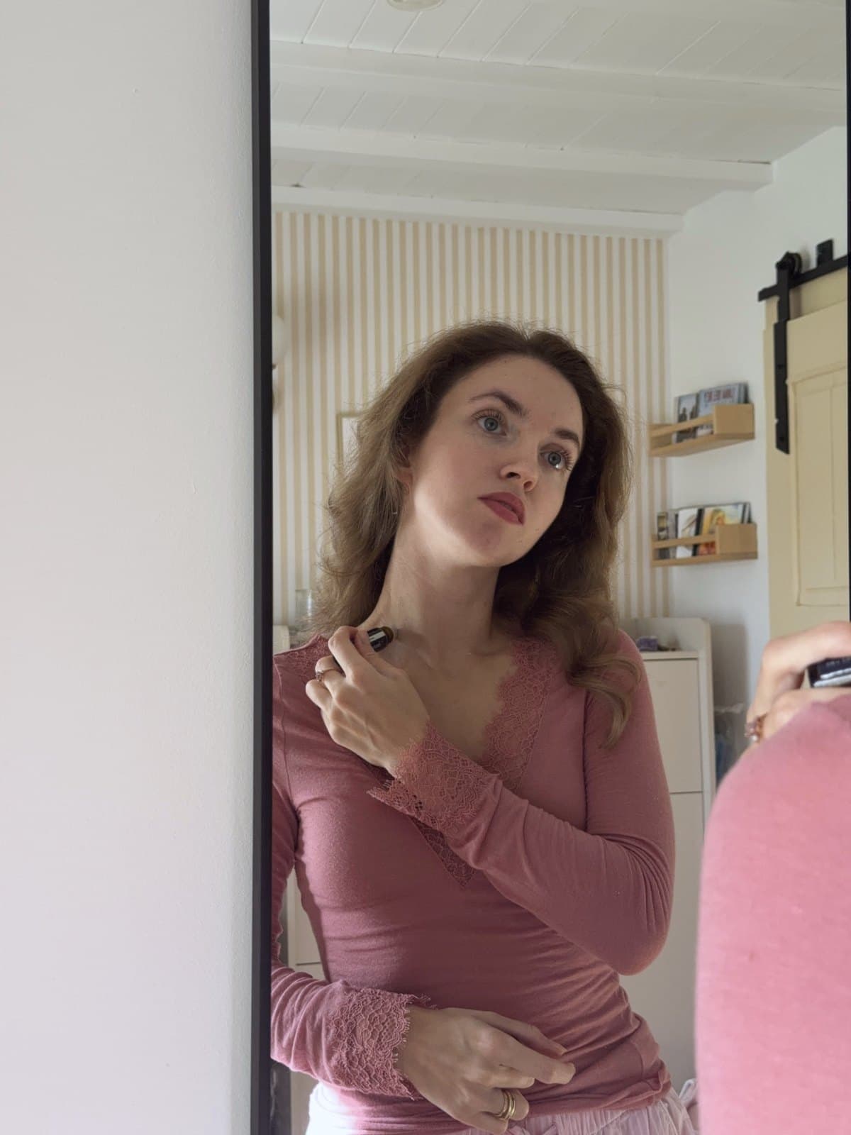 Izabela at the mirror, rolling Scent Primer on her neck